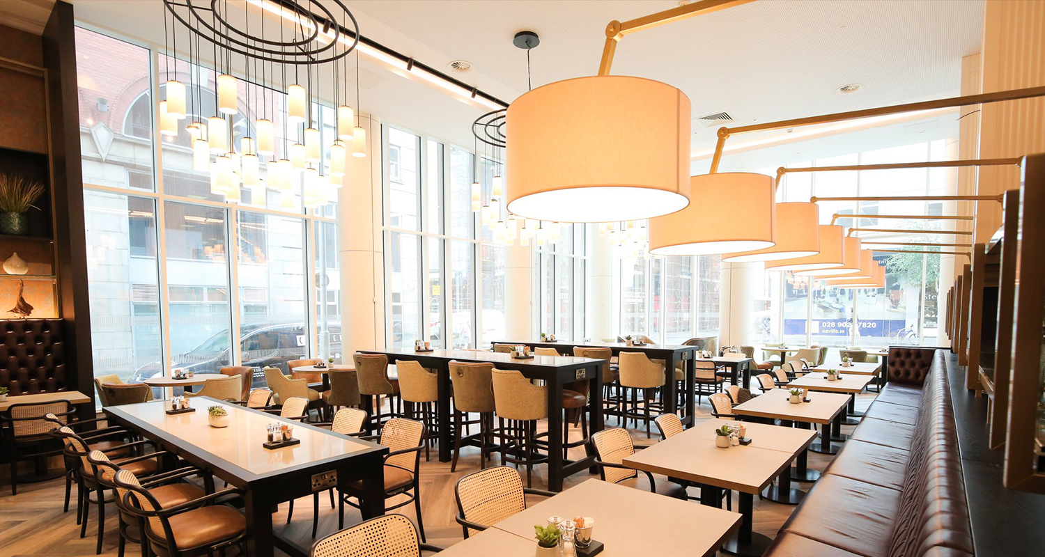 A row of Drum Silk Lampshades hanging over dinning tables at the restaurant