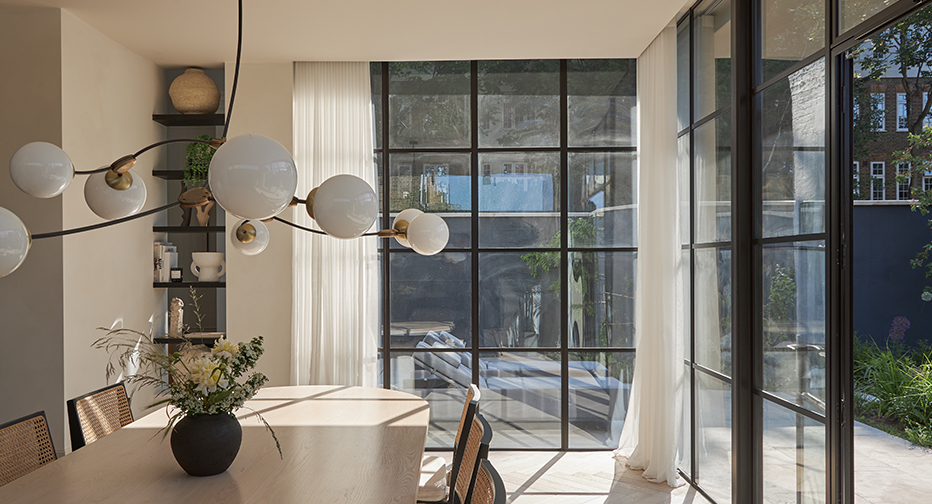 Contemporary dining area with bespoke VENESTRE sheer curtains on expansive steel-framed windows. Highlights luxury window treatments that maximise natural light and complement modern architectural interiors.