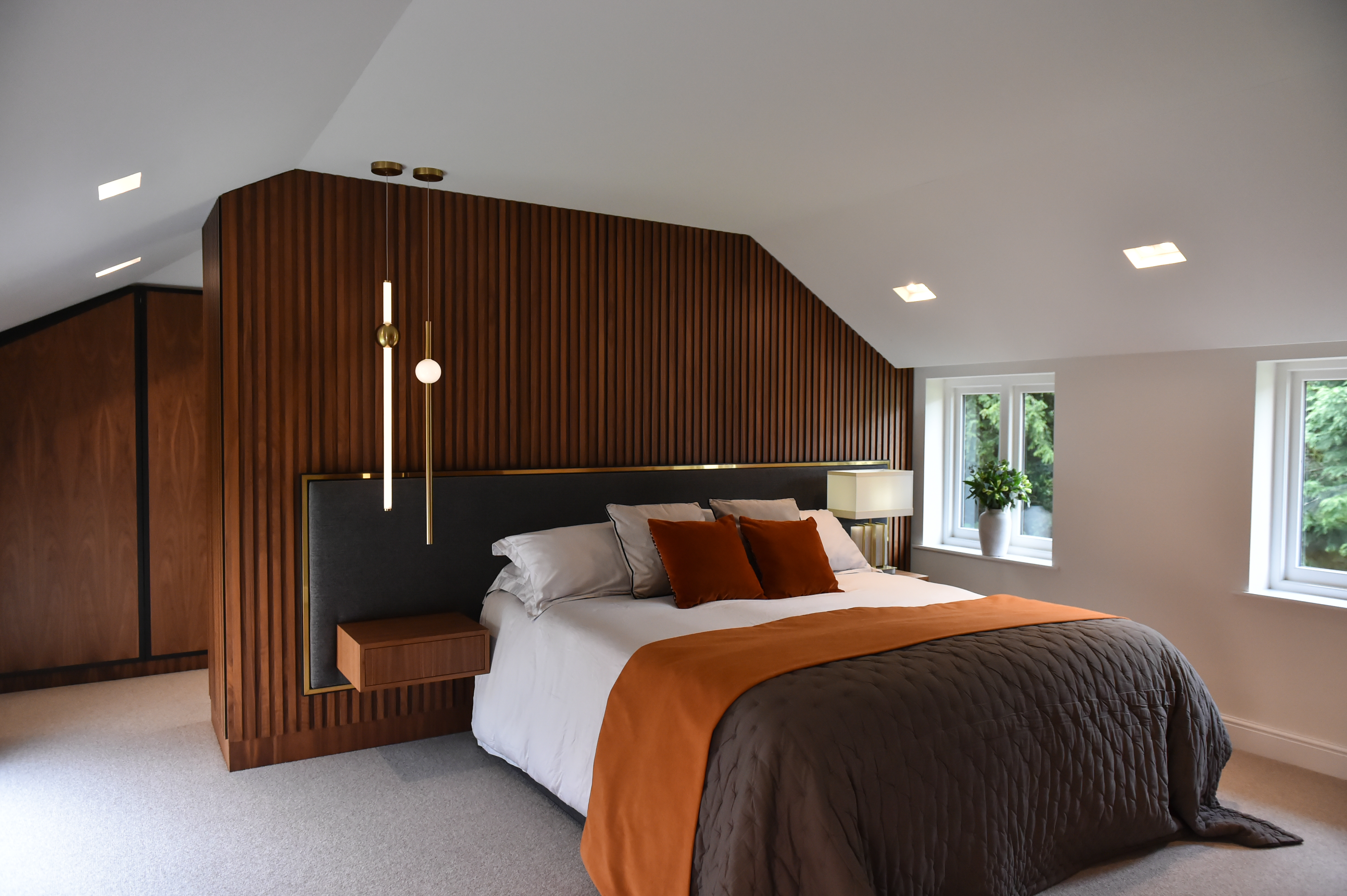 The centrepiece of this bedroom is a stunning slatted wall behind the upholstered headboard. With a finish in wood, this feature wall adds a contemporary touch while creating a cosy, inviting atmosphere.