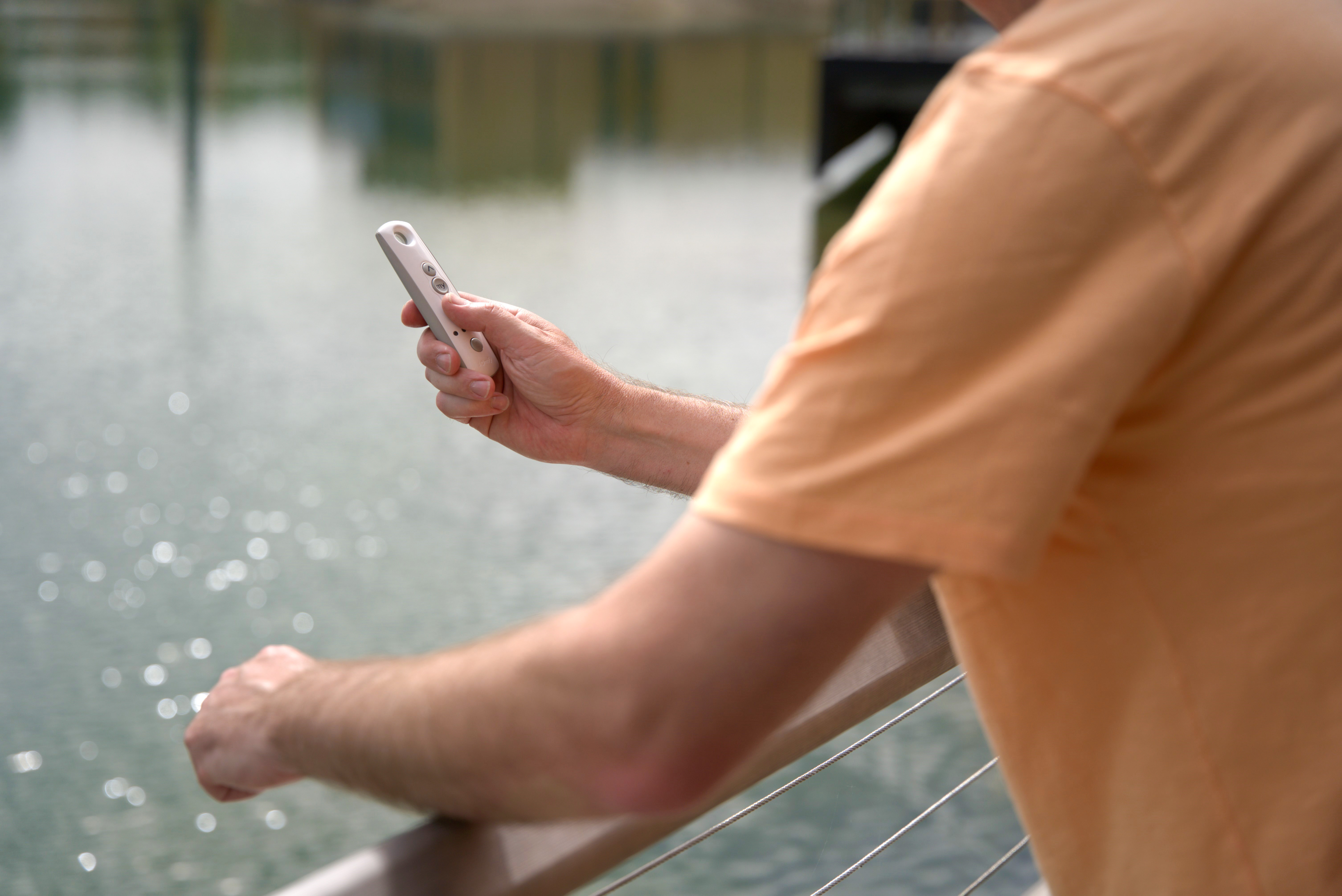 Man operating a Somfy remote next to a lake