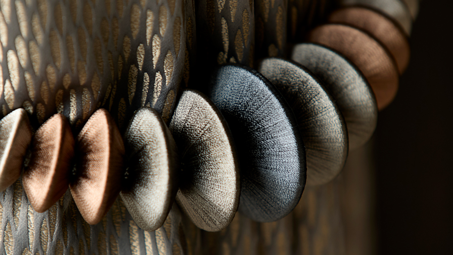 Close-up of luxury satin curtain tieback featuring multitone silk discs and metallic jacquard drapery, highlighting high-end interior design detailing