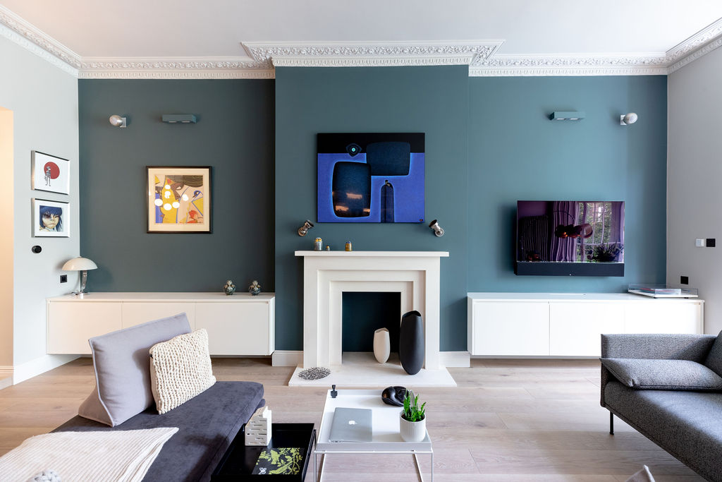 Lounge with blue feature wall with white fireplace and joinery. Modern artworks hang on the walls 