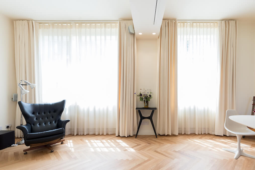 Beautiful flowing curtains dress the windows, parquet flooring and leather chair