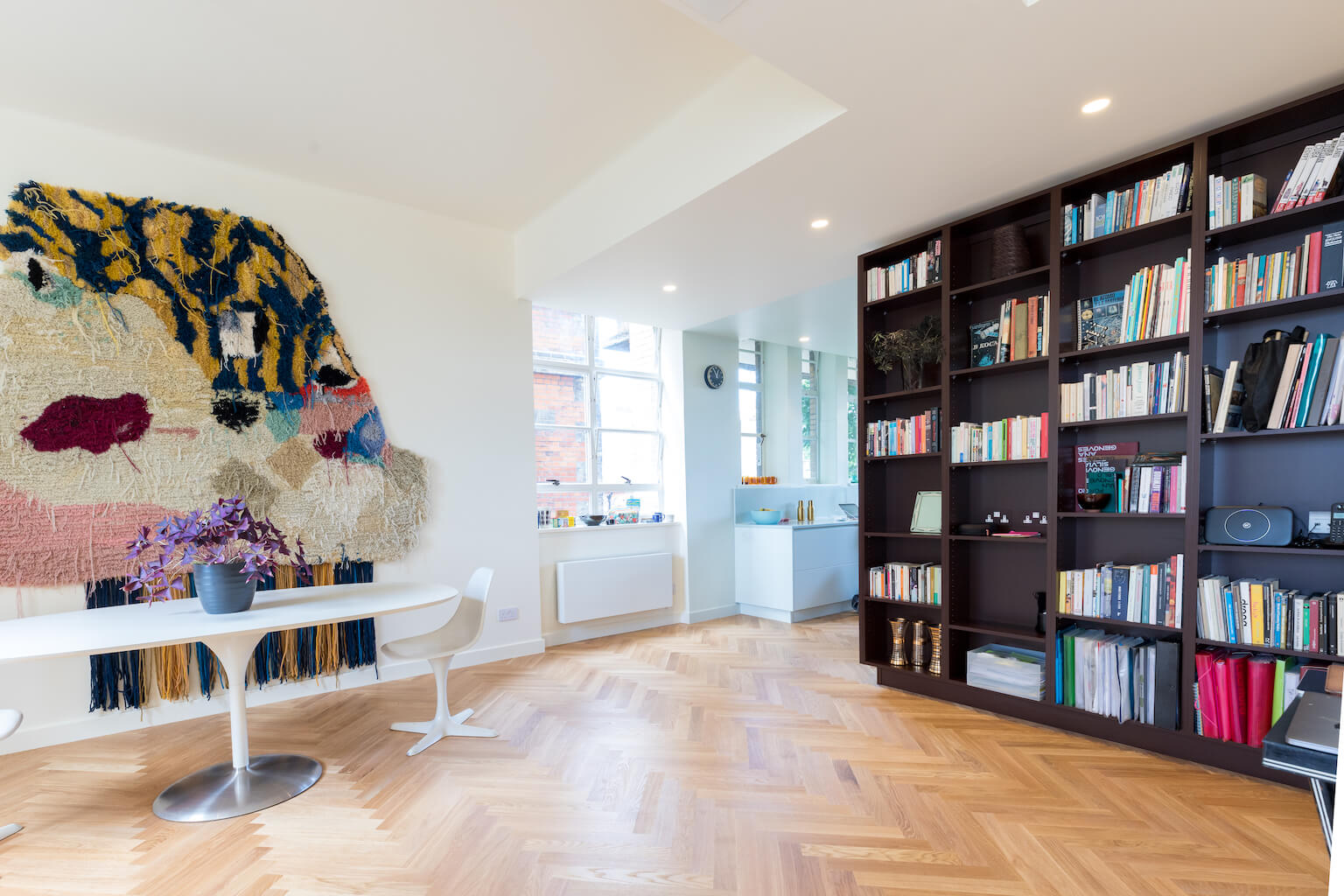 Large wall hanging with white modern table and dark bespoke shelving