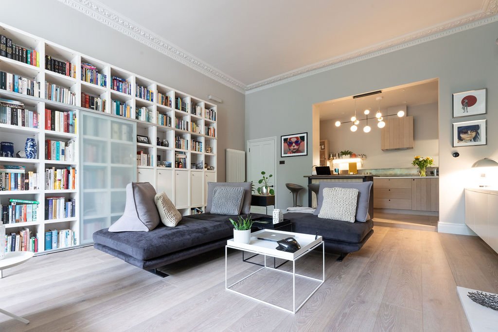 Modern lounge with large white shelving unit filled with books 