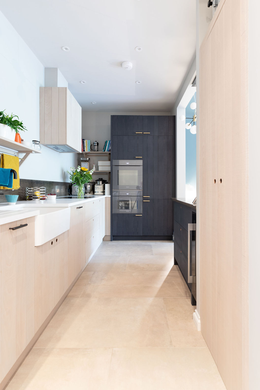 Chic light bespoke kitchen cabinetry either side with dark units at the far end 