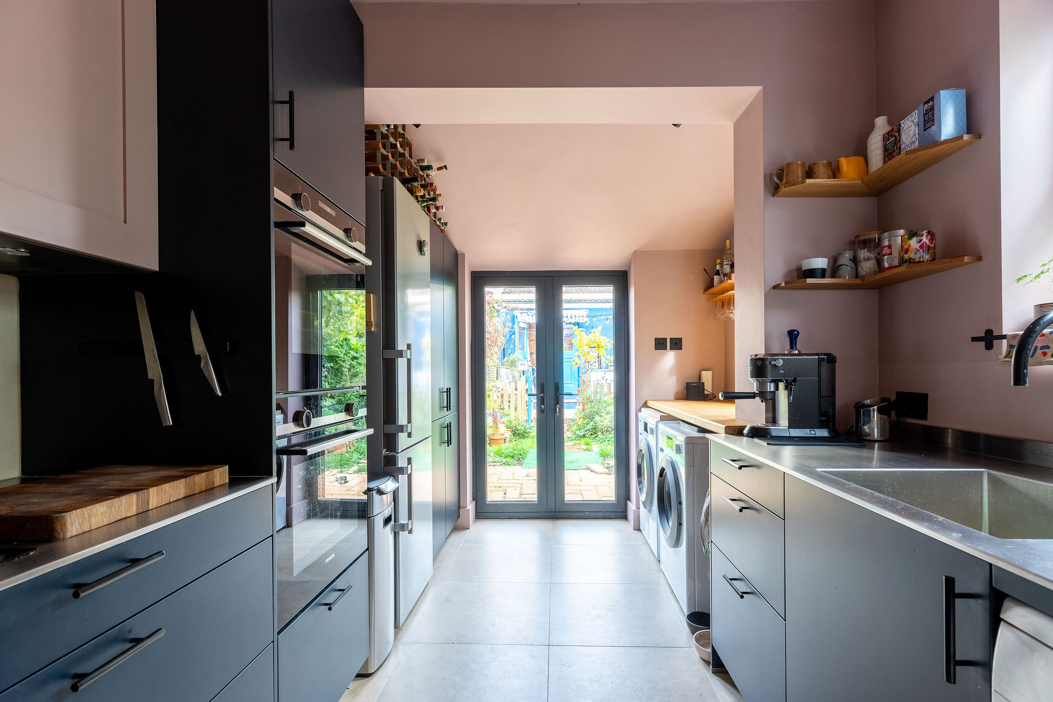 Pink drenched room with chic modern grey kitchen units 