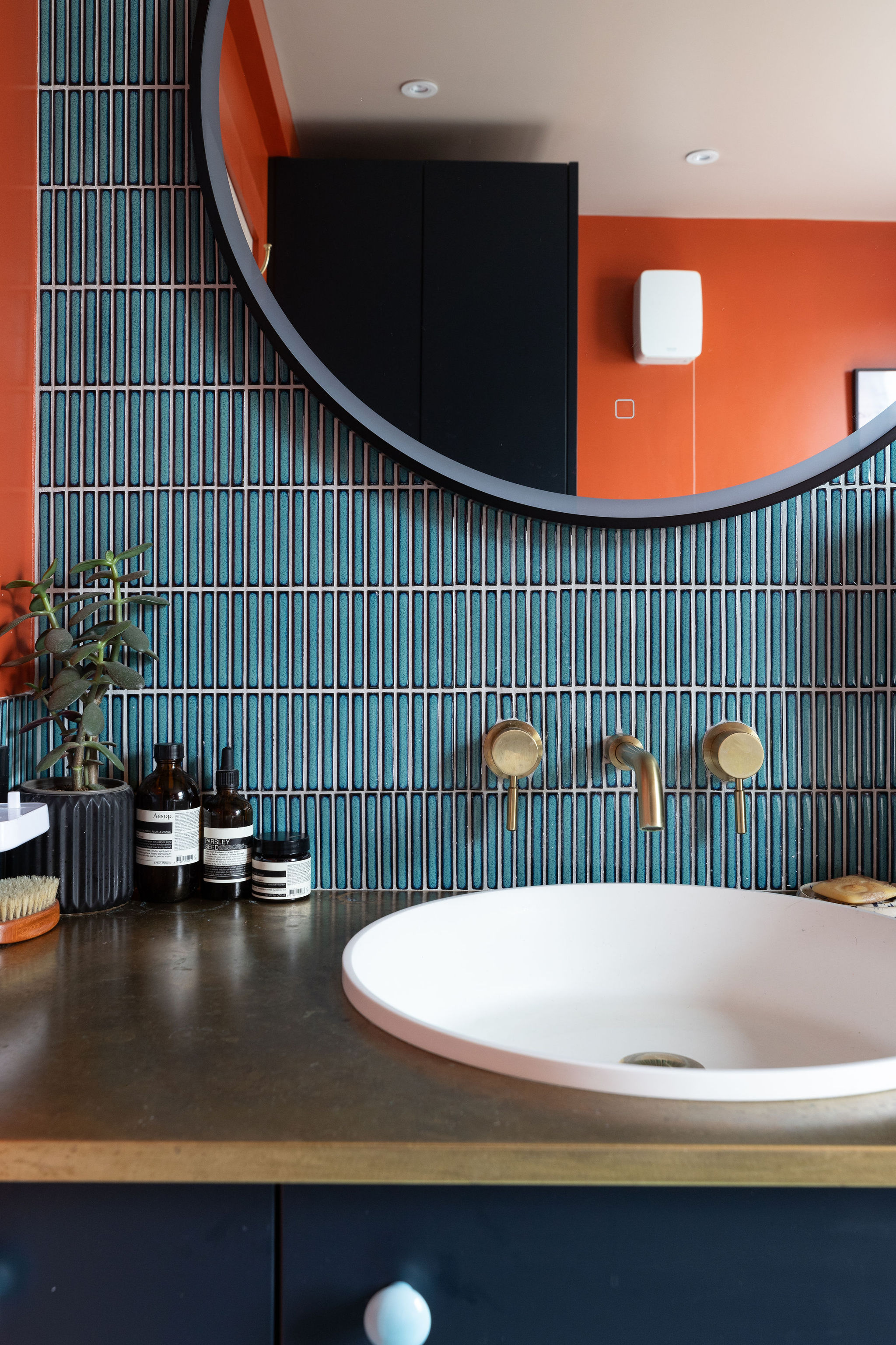 Stunning kitkat blue tile and orange bathroom walls reflected in mirror