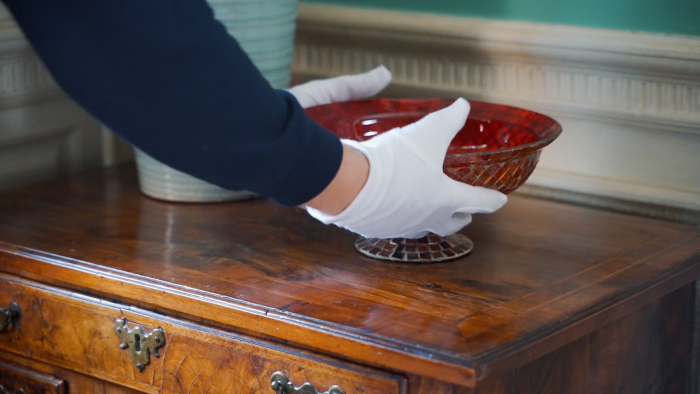 someone picking up a red glass bowl.