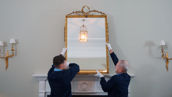 two men taking down a gilt mirror.