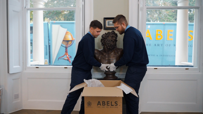 two men packing a bronze bust.