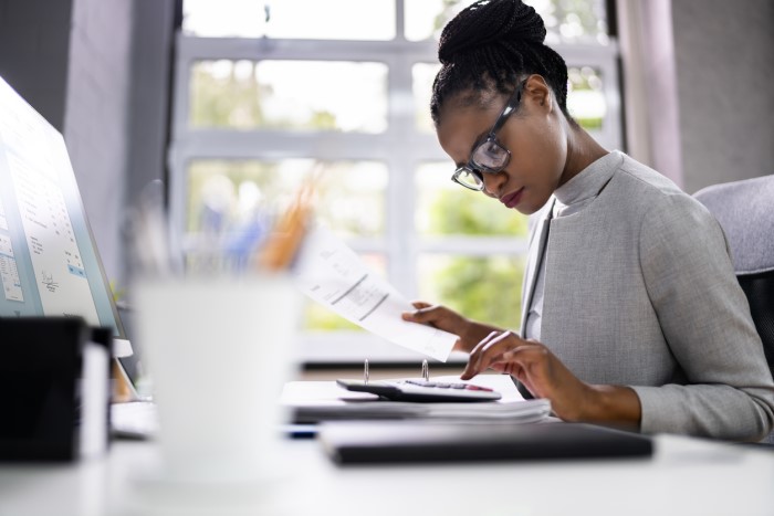 woman in glasses using a large calculator