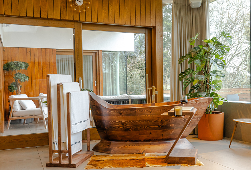 The Nautilus freestanding wooden bathtub by Dream Stuff Studio in a modern villa-style interior, surrounded by greenery and natural light.