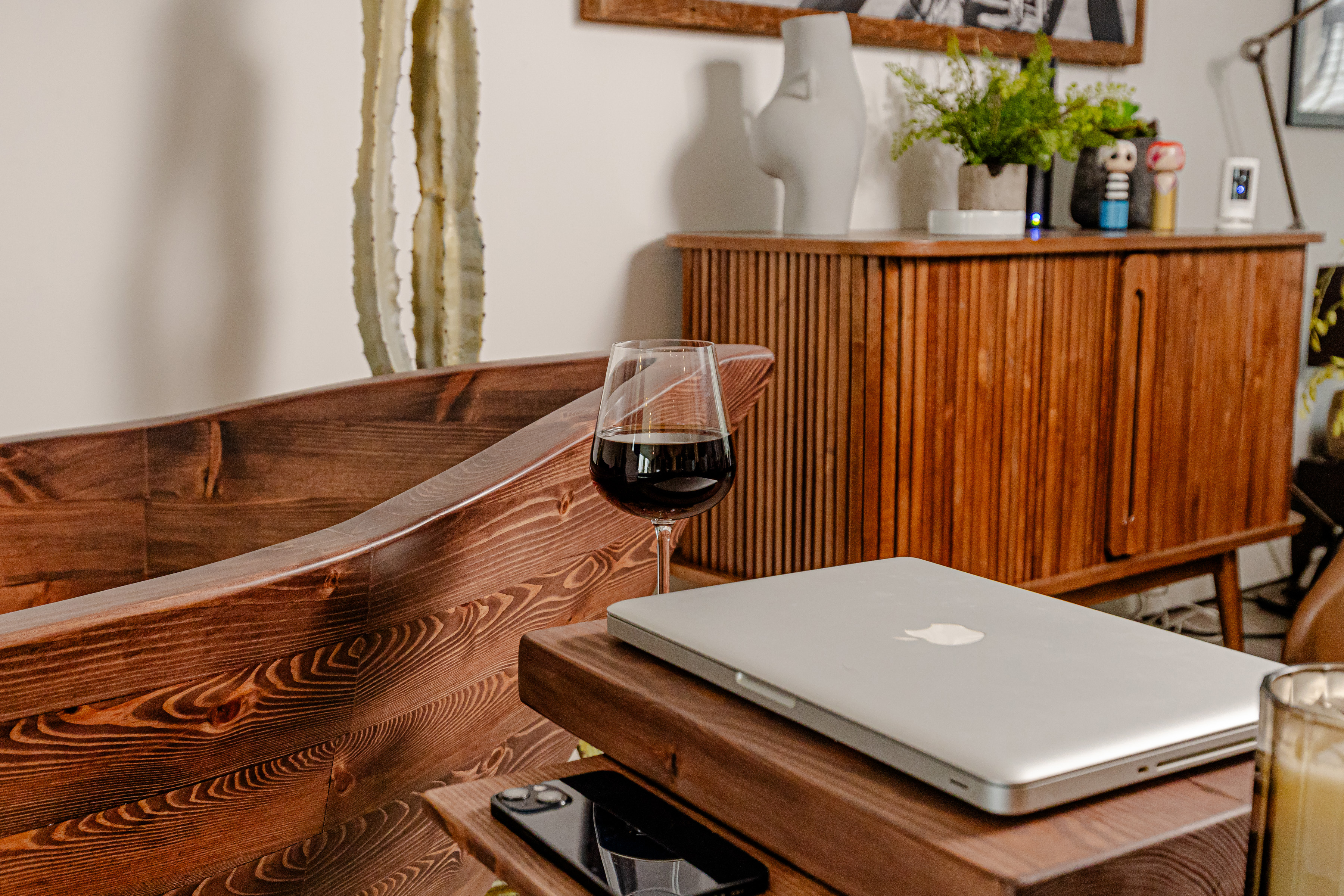 Close-up of the Nautilus wooden bathtub in an open-space cottage interior, styled with wine, laptop table, and warm wood textures for a relaxed living atmosphere.