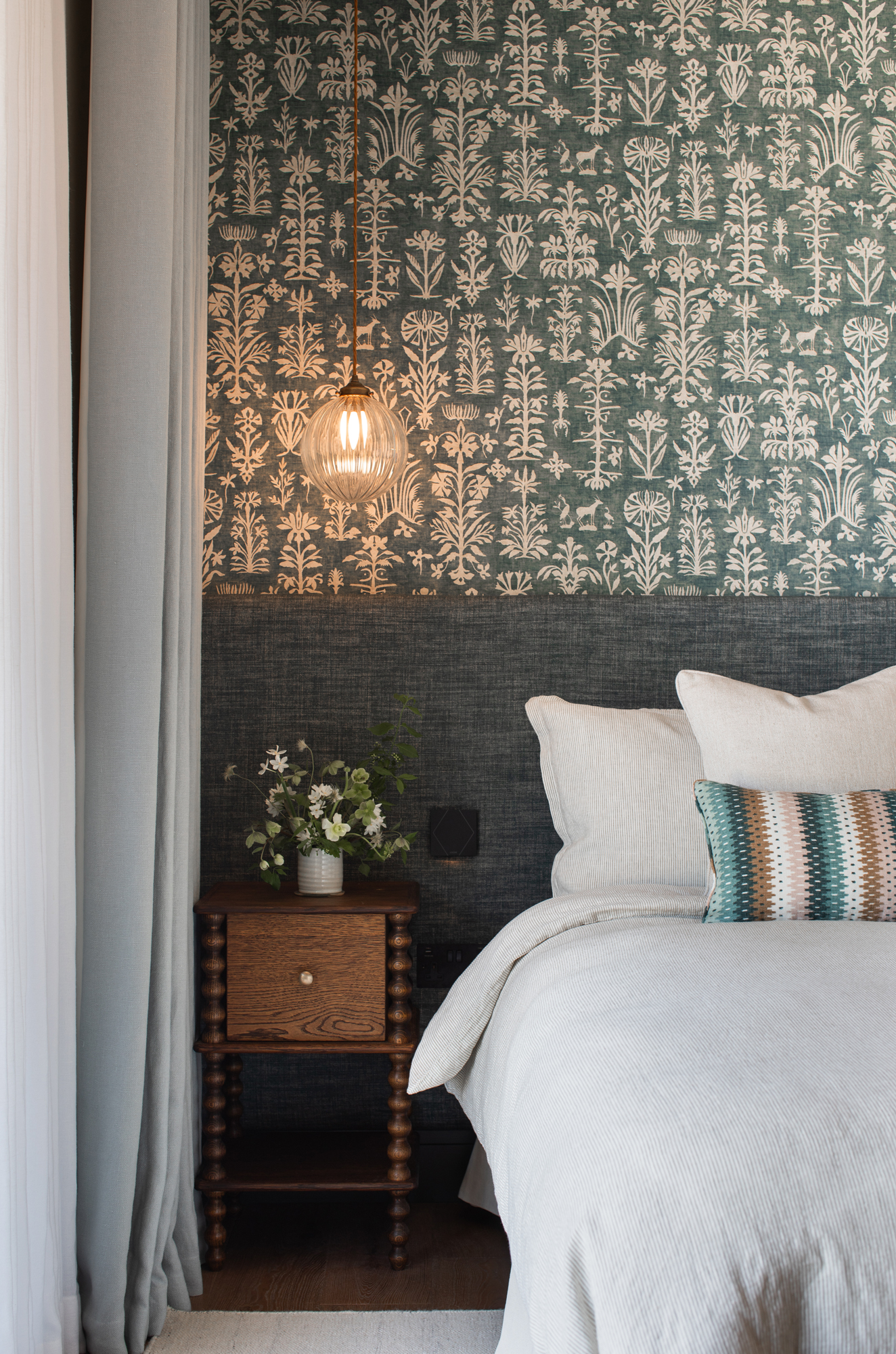 Layered bedroom interior within a contemporary riverside new build, combining patterned wall finishes, tailored lighting and bespoke furniture as part of a considered luxury interior architecture scheme.