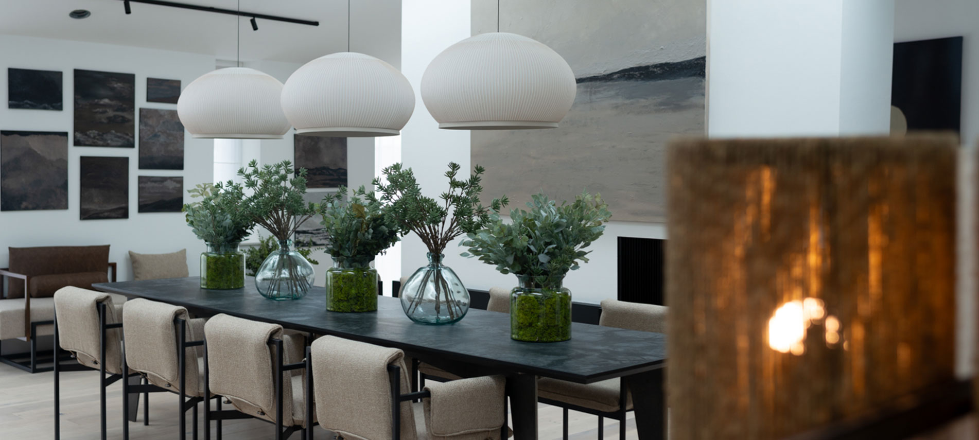 long table with greenery in vases.