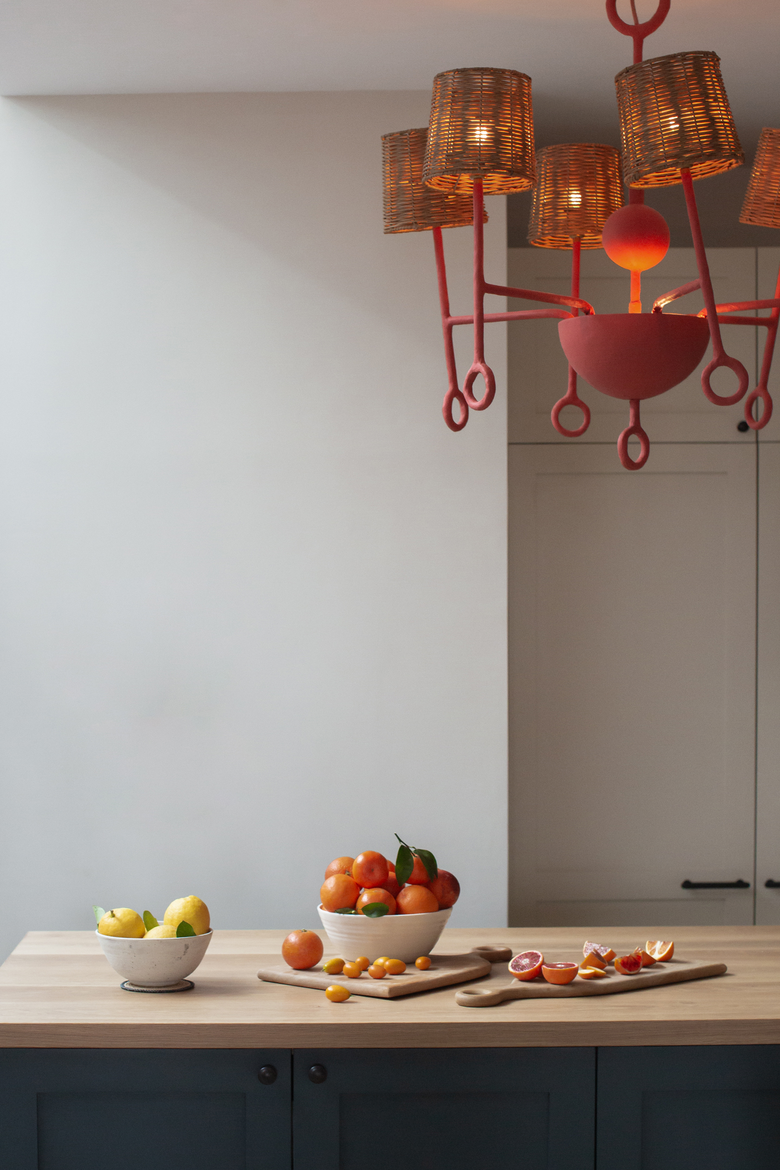 Kitchen island within a Victorian townhouse refurbishment, pairing contemporary lighting with simple materials and everyday styling as part of a characterful interior architecture scheme.