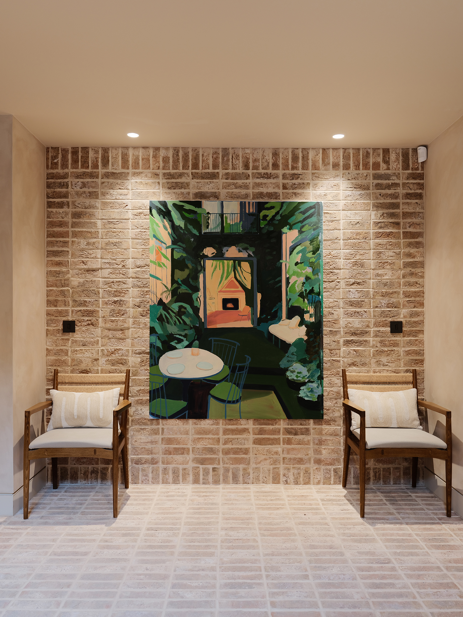 Stacked bond brick slip feature wall with artwork centrally and two chairs