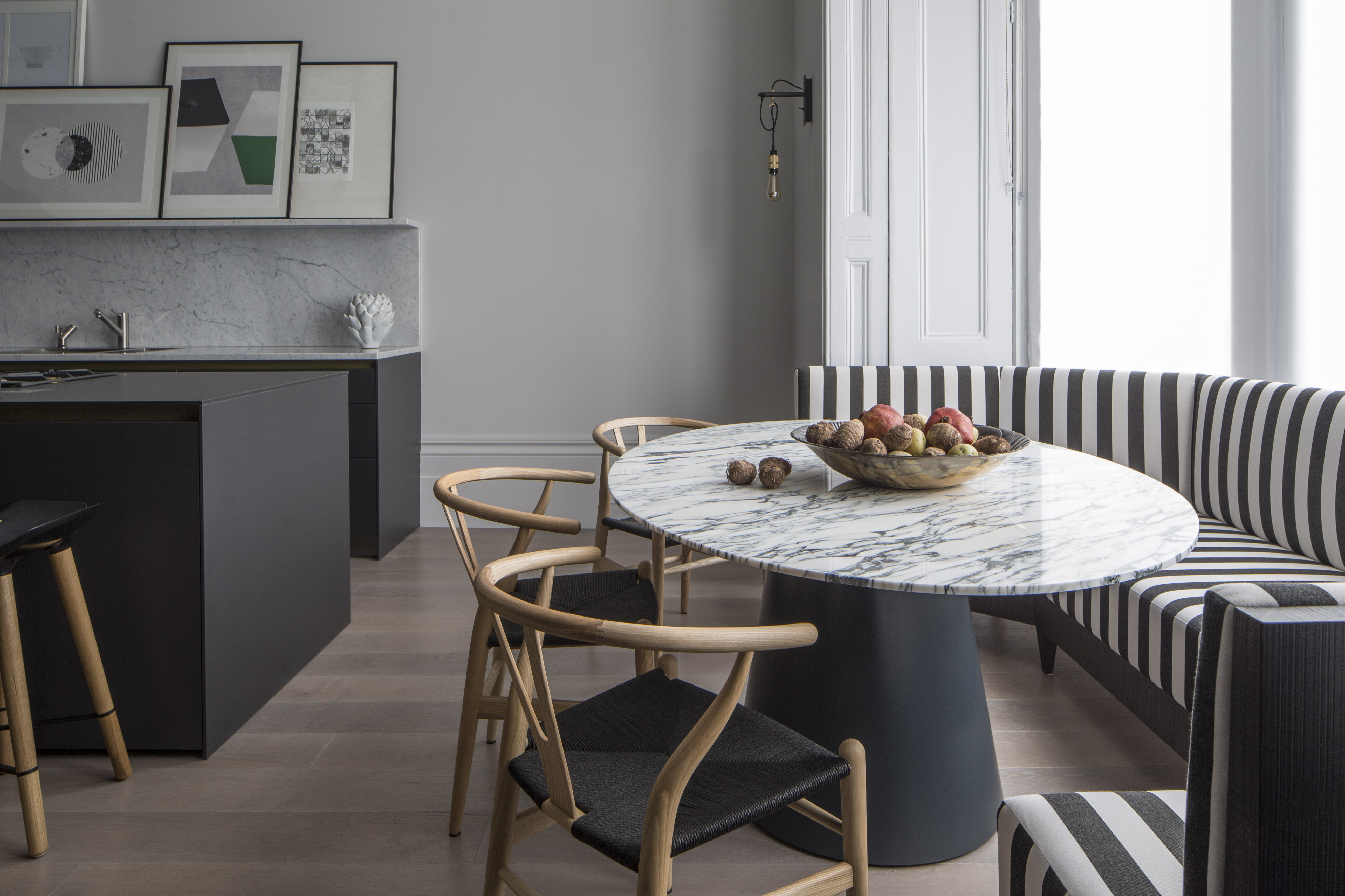 bay window seating with marble oval table and black and white striped banquette